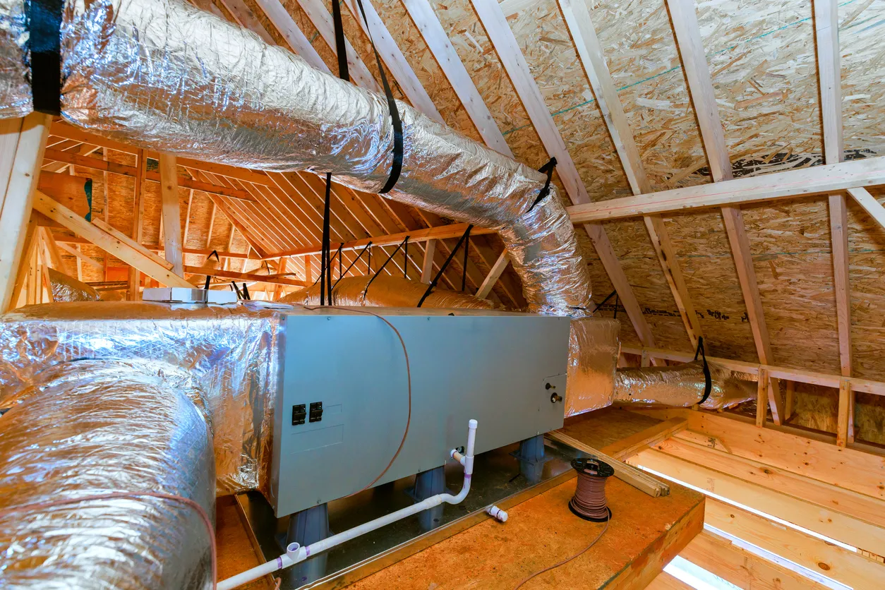 Attic air handler with foil-insulated flexible ductwork in unfinished wood-framed attic, new HVAC installation